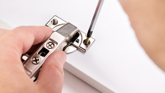 Close-Up Of Hinge Adjustment Using Screwdriver On White Cabinet Door