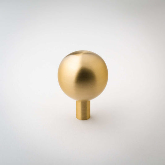 Dumas ball knob with a brushed brass surface