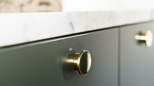Green cabinets with naturally aged brass door knobs for a vintage look