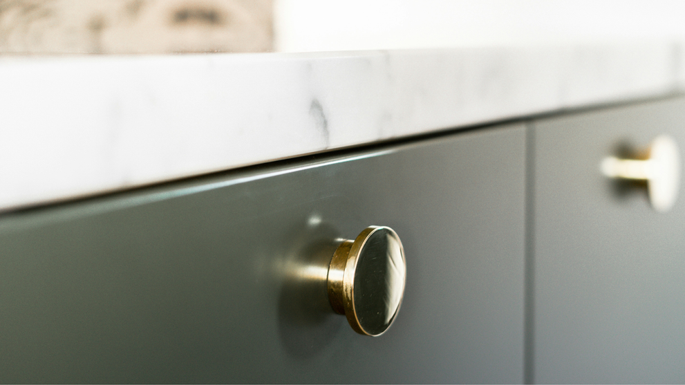 Green cabinets with naturally aged brass door knobs for a vintage look
