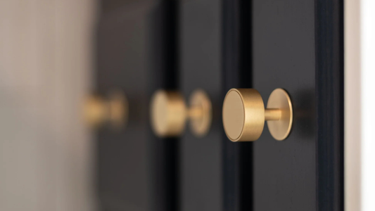 Inspire Hardware’s Gateau, solid brass knobs paired with black cabinets