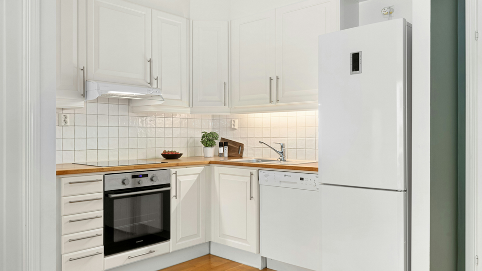Minimalist kitchen with white partial overlay cabinets and polished nickel cabinet hardware