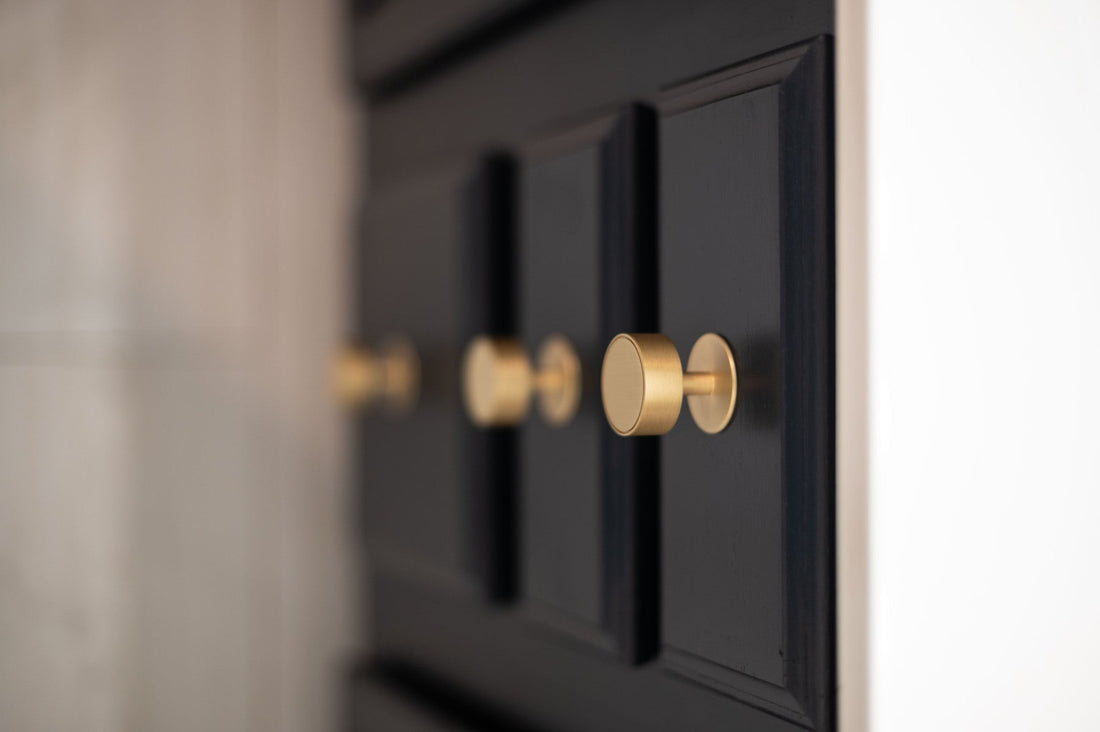 Close view of a Gateau brass knob on a dark bathroom vanity door