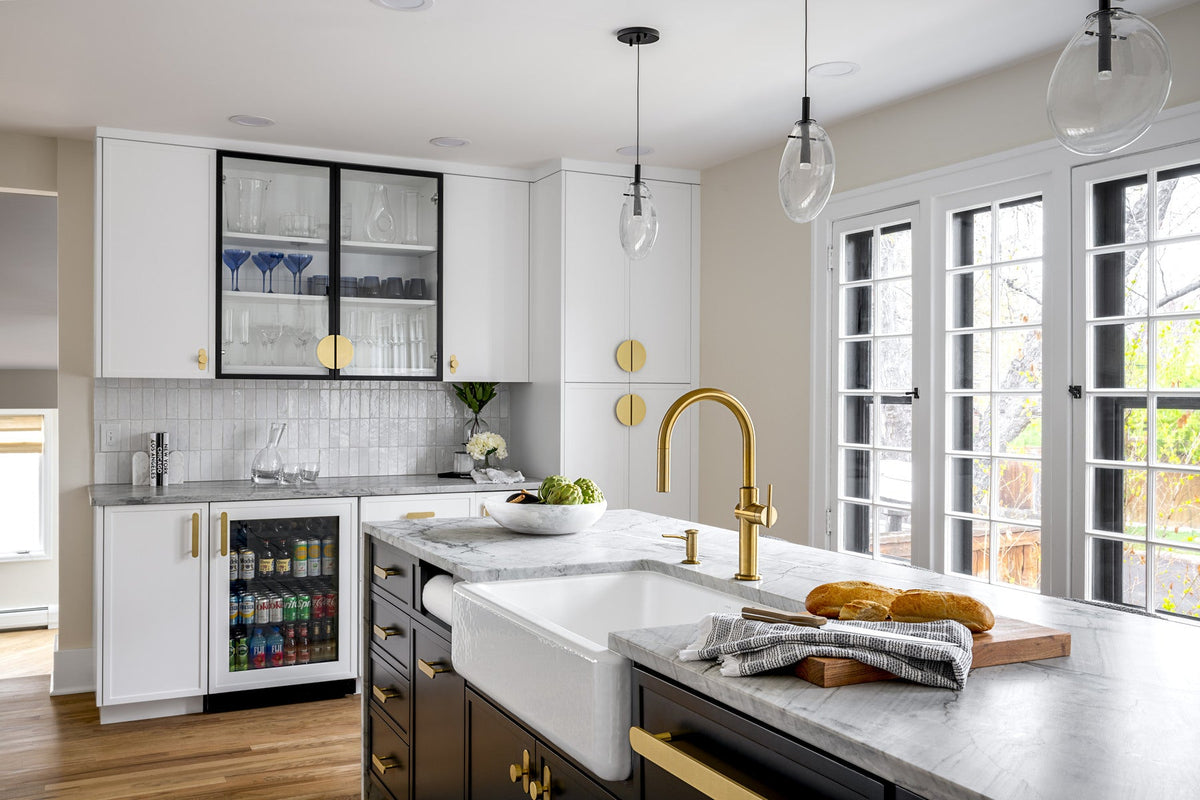 White kitchen and dark island with coordinated brass cabinet hardware