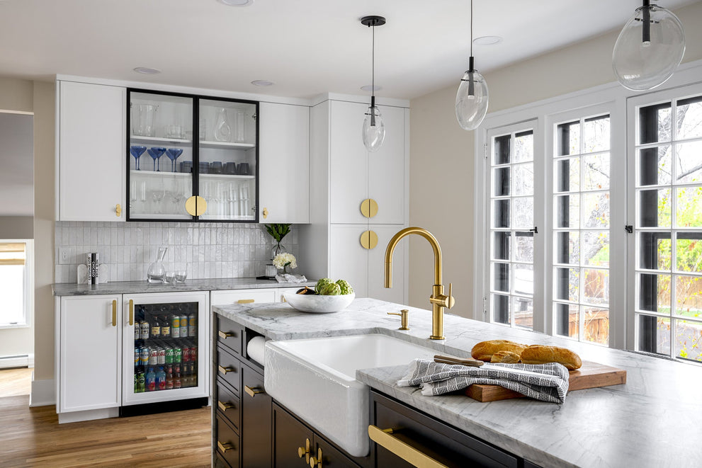 White kitchen and dark island with coordinated brass cabinet hardware