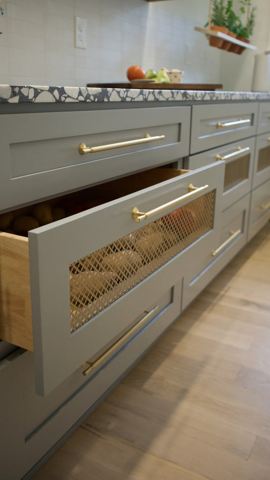 Partly open wide pantry drawer with a brass Tuxedo cabinet pull