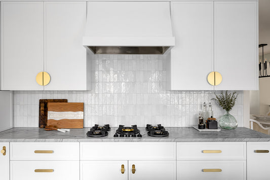White kitchen with half-moon brass cabinet pulls and long rounded drawer pulls