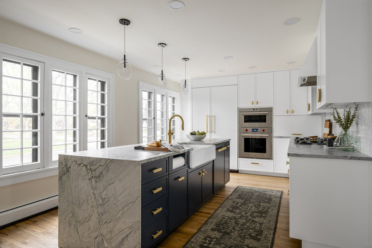 Bright kitchen with clean cabinet fronts, brass pulls and a dark island