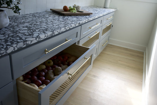 Open produce drawer and adjacent pantry drawers fitted with brass Tuxedo pulls