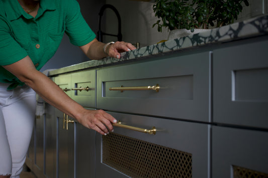 Hand opening a pantry drawer using a brass Tuxedo cabinet pull