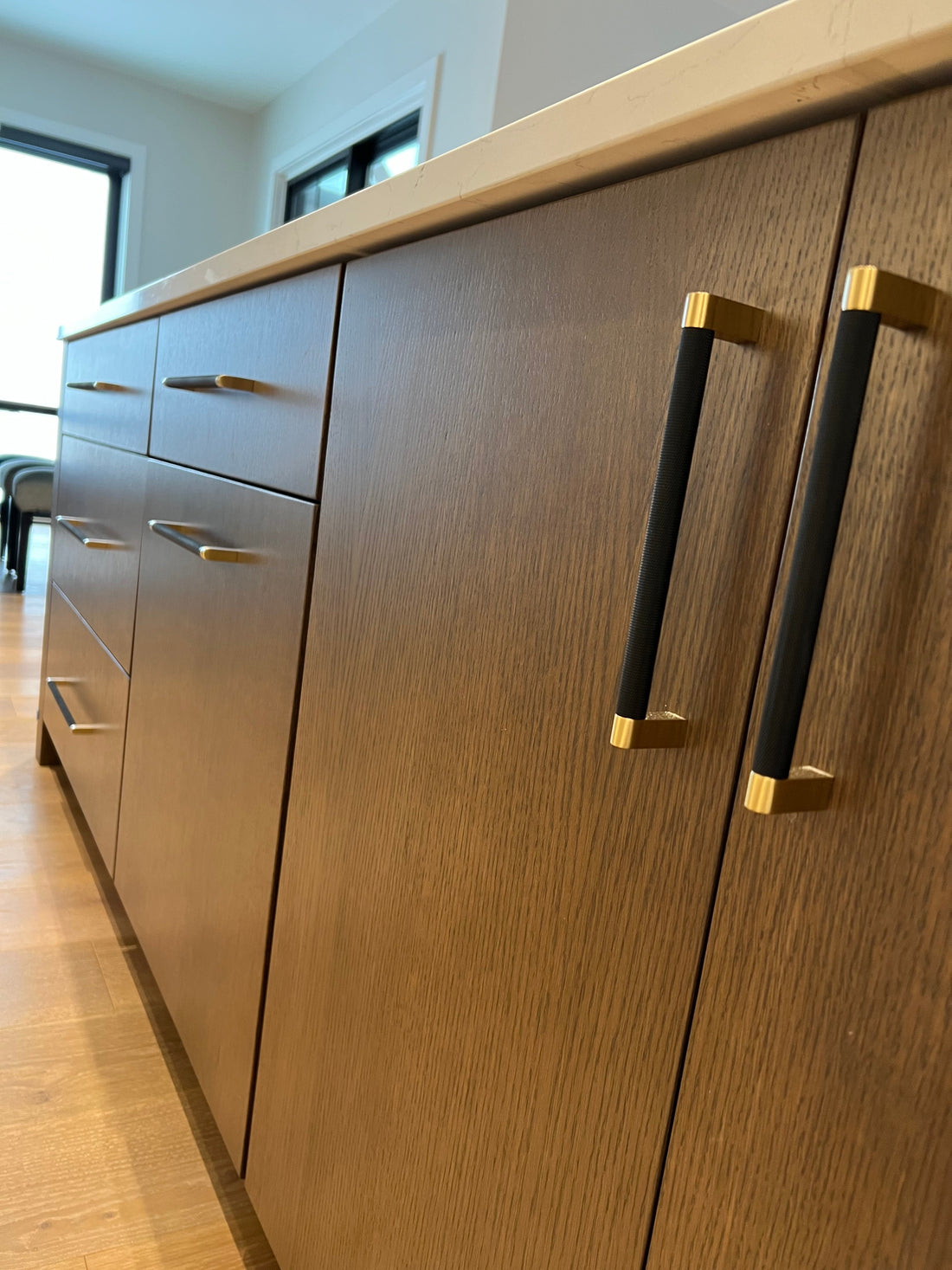 Bold black and brass pulls mounted vertically on flat wood cabinet doors