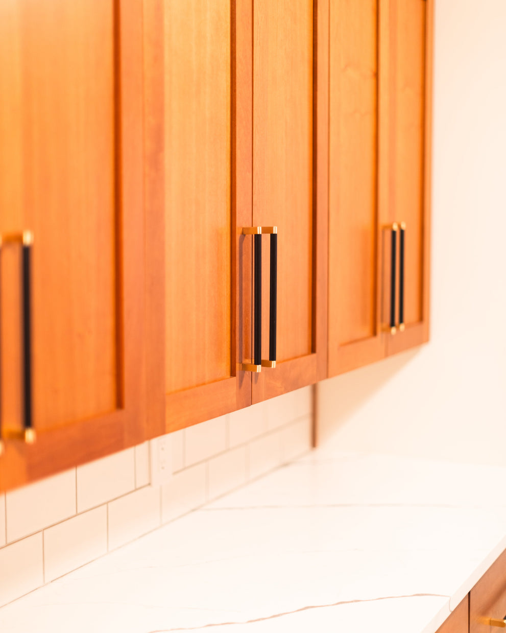 Bold black and brass cabinet pulls on framed wood kitchen doors