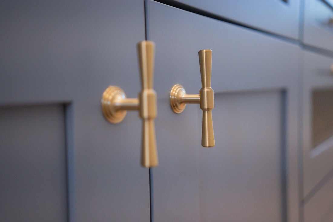 Tuxedo brass knobs mounted on blue-gray inset cabinet doors