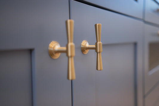 Tuxedo brass knobs mounted on blue-gray inset cabinet doors