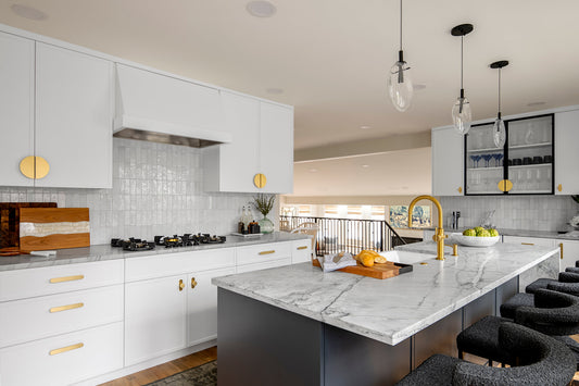 White kitchen with a dark island, half-moon upper cabinet pulls and brass drawer pulls