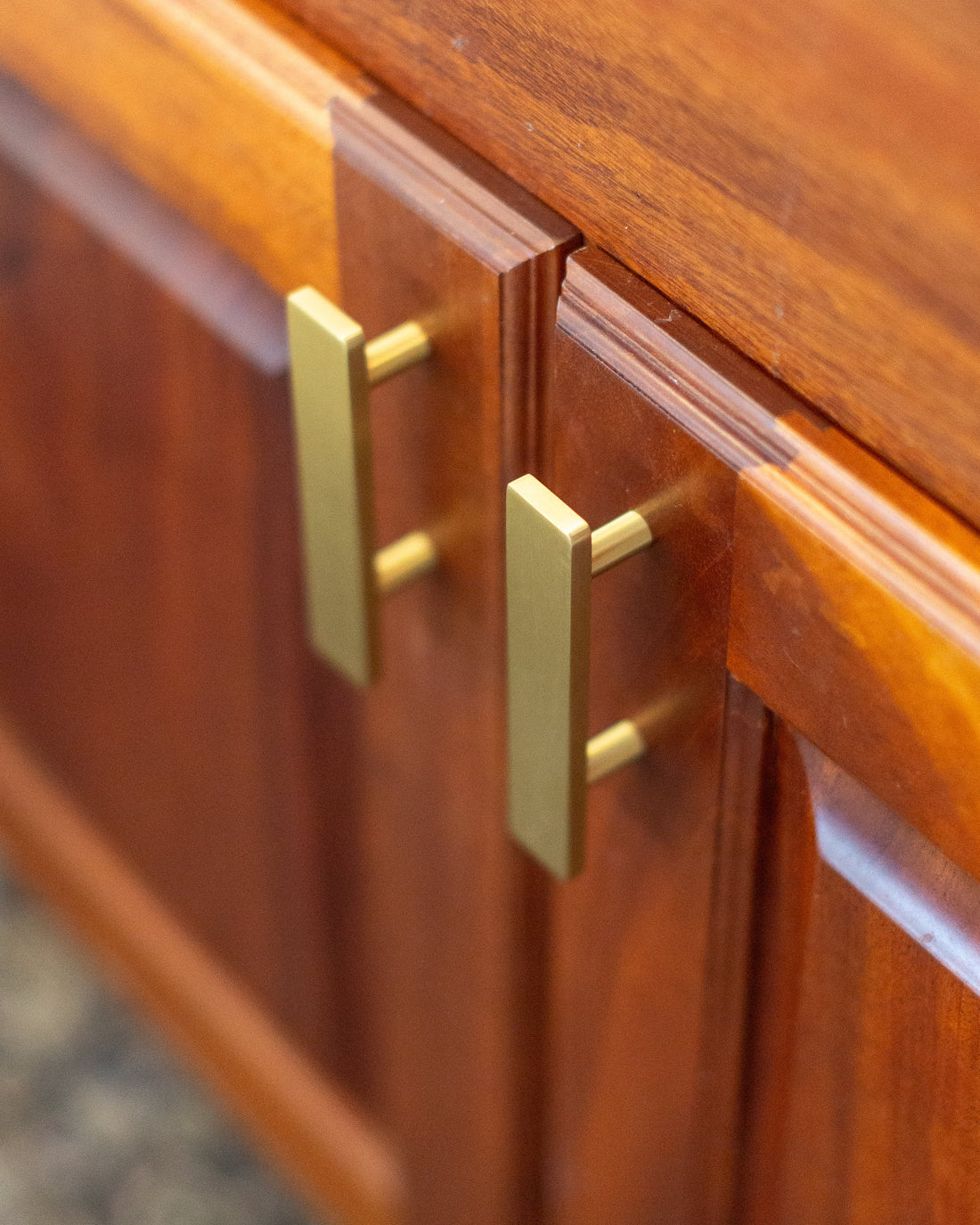 Two Auburn brass pulls aligned vertically on wood cabinet doors