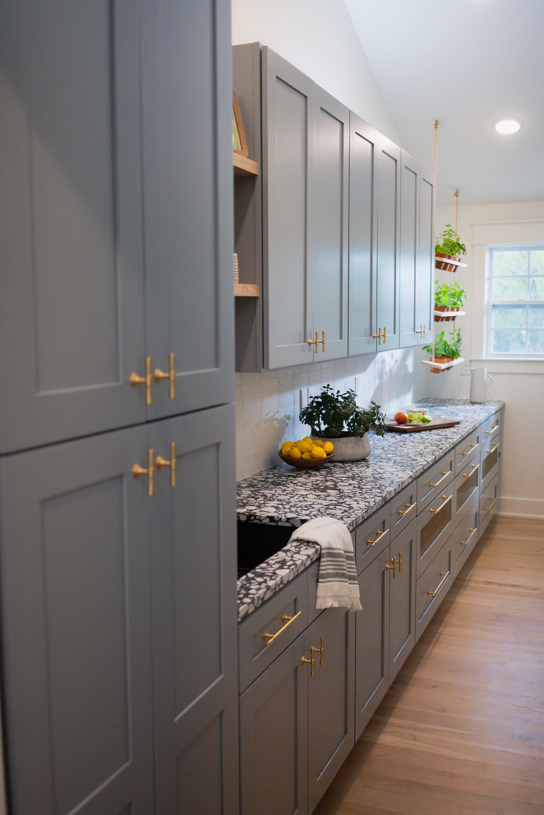 Tall pantry cabinetry with brass Tuxedo knobs and matching drawer pulls
