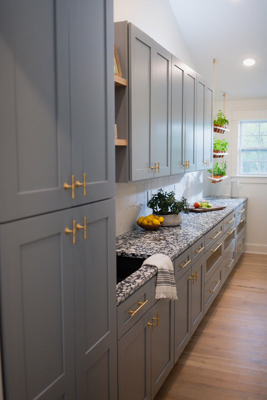 Tall pantry cabinetry with brass Tuxedo knobs and matching drawer pulls