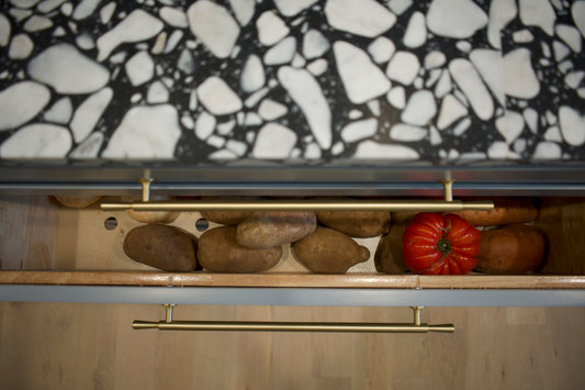 Overhead view of an open wide pantry drawer with a brass Tuxedo pull