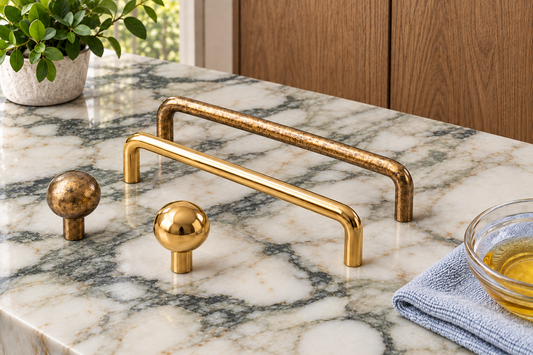 AI-assisted illustration of Inspire Arch pulls and Dumas knobs in polished and aged brass on natural marble with oak cabinets